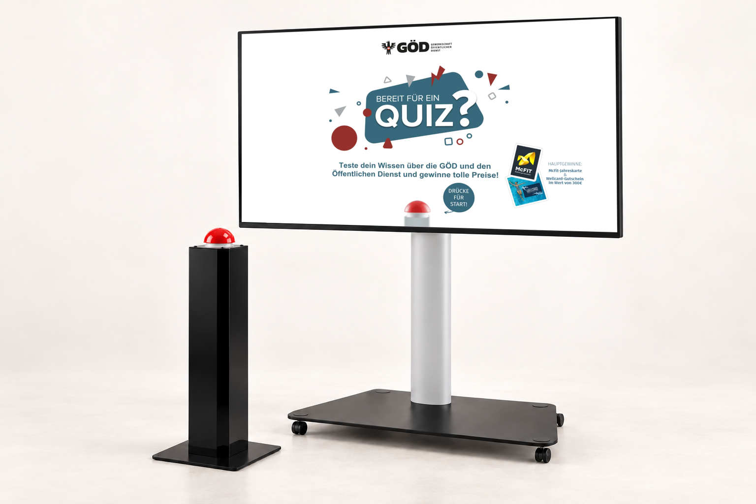 GAMIFY Quiz Setup: Bildschirm auf fahrbarem Standfuß mit GÖD Quiz Startscreen und daneben eine Buzzer-Stele mit rotem Buzzer